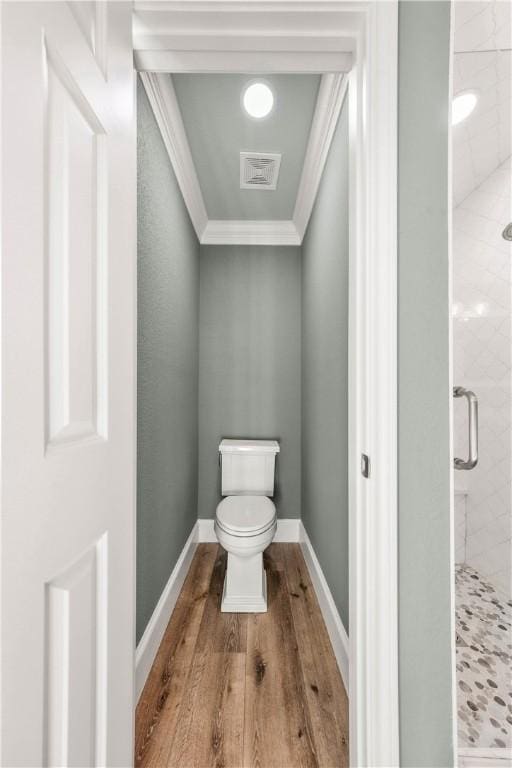 bathroom featuring a shower with door, ornamental molding, hardwood / wood-style floors, and toilet