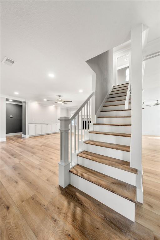 staircase with hardwood / wood-style floors and ceiling fan