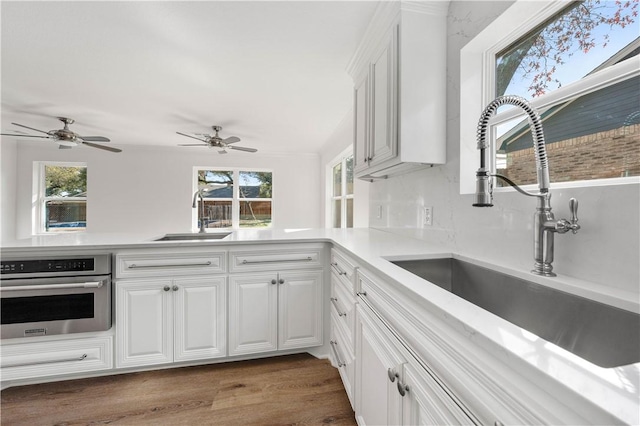 kitchen featuring white cabinetry, sink, hardwood / wood-style flooring, and stainless steel oven