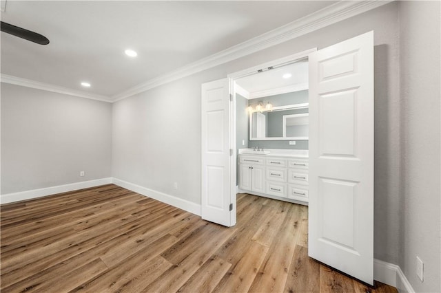 interior space with crown molding, sink, and light hardwood / wood-style floors