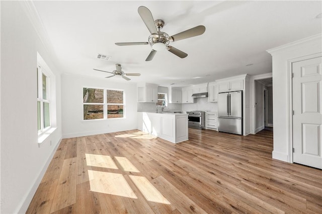 unfurnished living room featuring ceiling fan, ornamental molding, sink, and light wood-type flooring