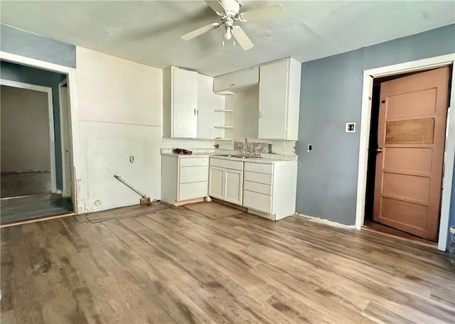 kitchen featuring ceiling fan, white cabinetry, sink, and light hardwood / wood-style flooring