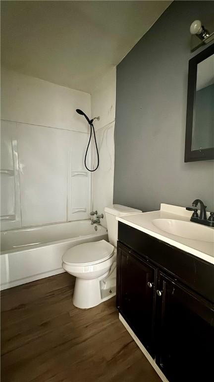 full bathroom with shower / tub combination, vanity, wood-type flooring, and toilet