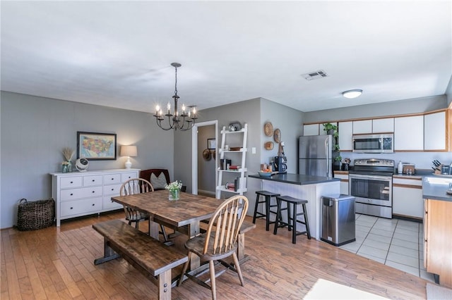 dining space featuring light wood-style flooring, visible vents, and a notable chandelier