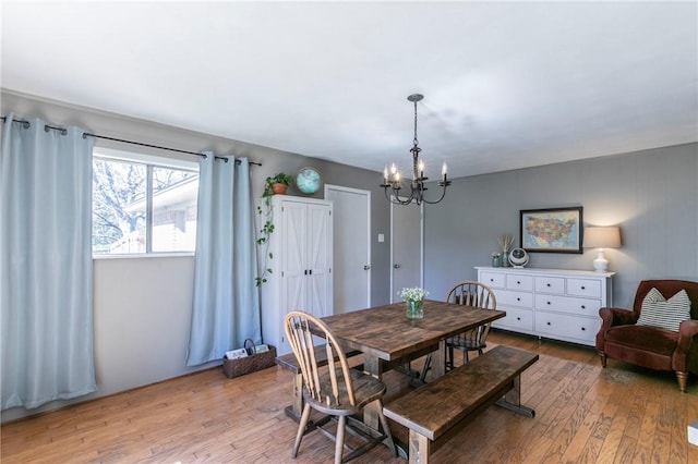 dining space with light wood finished floors and an inviting chandelier