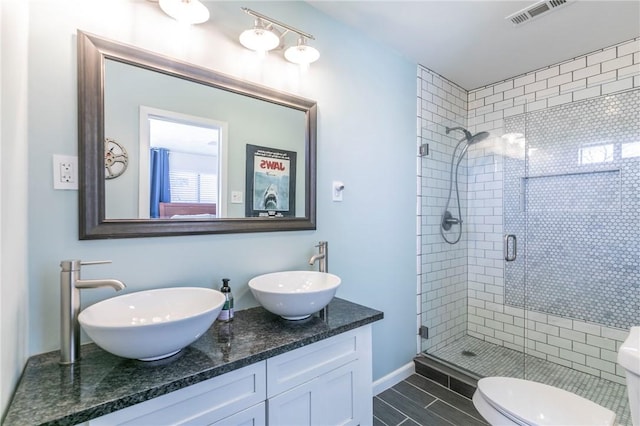 full bathroom featuring double vanity, a stall shower, a sink, and visible vents