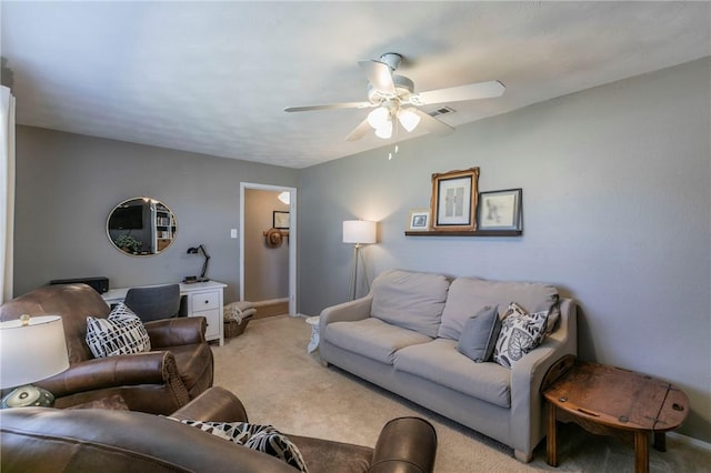 living area featuring baseboards, a ceiling fan, and light colored carpet