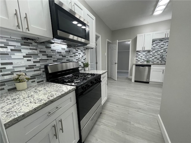 kitchen featuring white cabinetry, light stone countertops, decorative backsplash, and stainless steel appliances