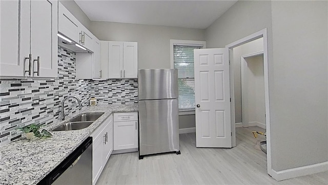 kitchen with light stone countertops, white cabinetry, stainless steel appliances, decorative backsplash, and sink