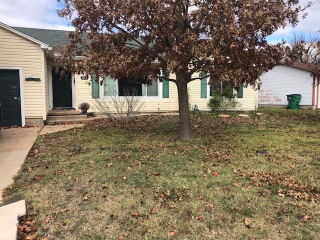 view of property hidden behind natural elements featuring a garage and a front yard