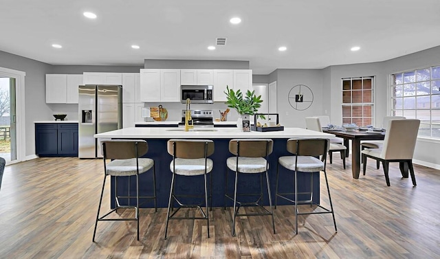 kitchen featuring a breakfast bar, sink, white cabinetry, an island with sink, and stainless steel appliances