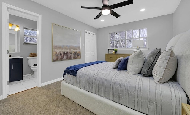 bedroom with ceiling fan, light colored carpet, ensuite bath, and a closet