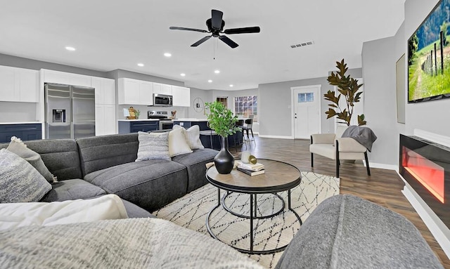 living room featuring ceiling fan and dark hardwood / wood-style flooring