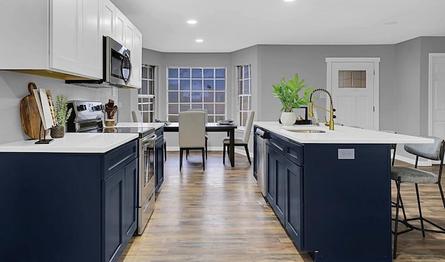 kitchen featuring sink, a breakfast bar area, blue cabinetry, and appliances with stainless steel finishes