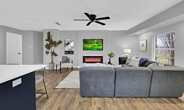 living room featuring dark wood-type flooring and ceiling fan