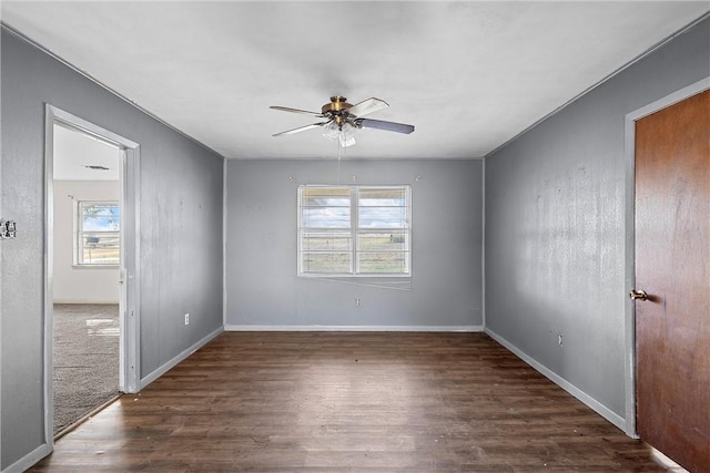 empty room featuring a wealth of natural light, ceiling fan, and dark hardwood / wood-style floors