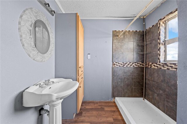 bathroom featuring tiled shower, wood-type flooring, and a textured ceiling