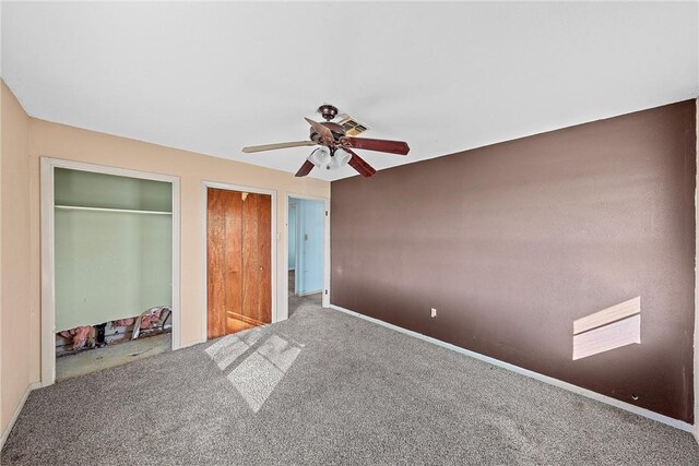 unfurnished bedroom featuring carpet flooring, multiple closets, and ceiling fan