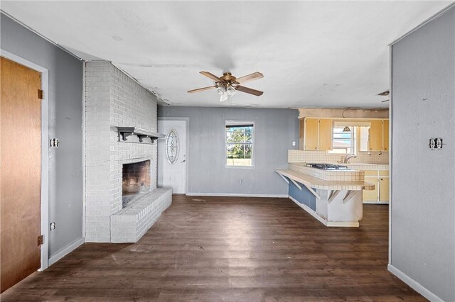 kitchen featuring a breakfast bar area, tasteful backsplash, a fireplace, and dark hardwood / wood-style floors