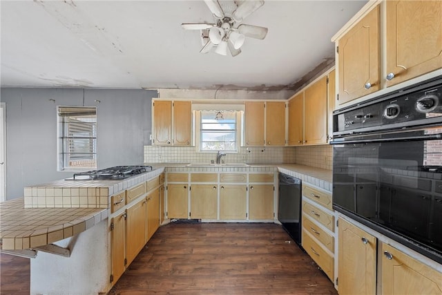 kitchen with tasteful backsplash, dark wood-type flooring, sink, black appliances, and tile counters