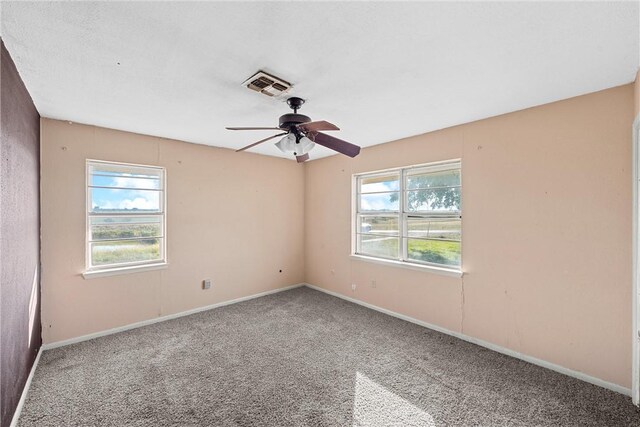 empty room featuring carpet, ceiling fan, and a healthy amount of sunlight