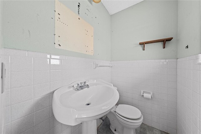 bathroom featuring sink, toilet, and tile walls