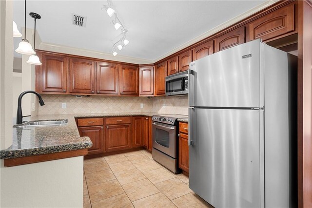 kitchen with dark stone counters, sink, hanging light fixtures, light tile patterned flooring, and stainless steel appliances