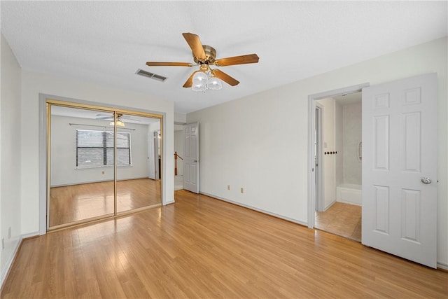 unfurnished bedroom with a textured ceiling, light hardwood / wood-style flooring, a closet, and ceiling fan