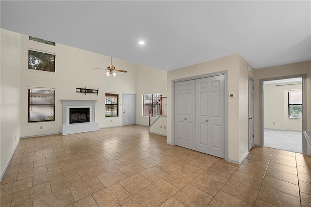 unfurnished living room with ceiling fan, a fireplace, and light tile patterned floors