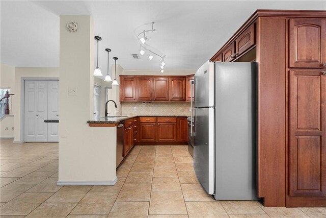 kitchen with stone countertops, sink, decorative backsplash, stainless steel fridge, and decorative light fixtures