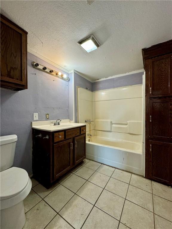 full bathroom with tile patterned flooring, a textured ceiling, toilet, and shower / bathtub combination