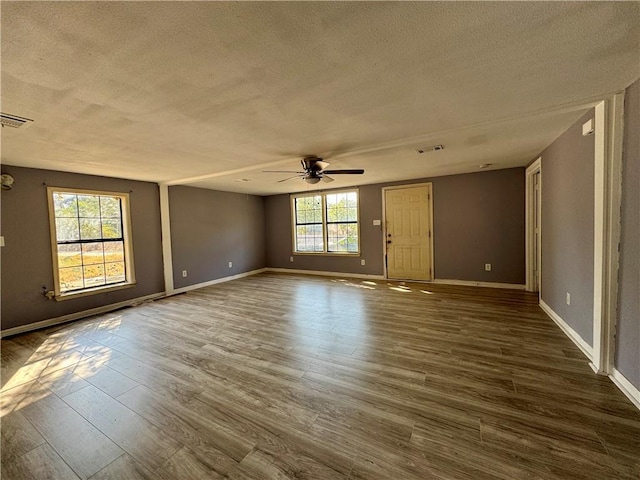 spare room with a textured ceiling, ceiling fan, a healthy amount of sunlight, and dark hardwood / wood-style floors