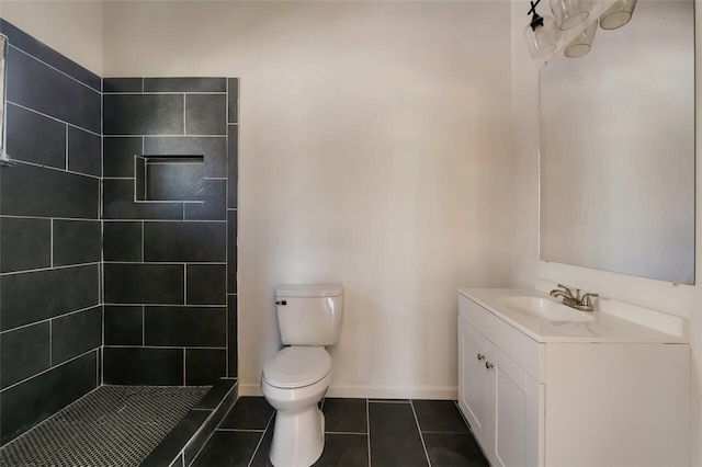 bathroom with tile patterned flooring, toilet, a tile shower, and vanity