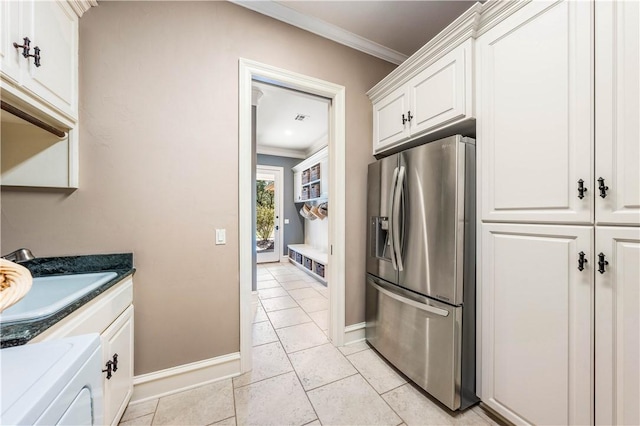 kitchen featuring sink, stainless steel fridge with ice dispenser, washer / dryer, white cabinets, and ornamental molding