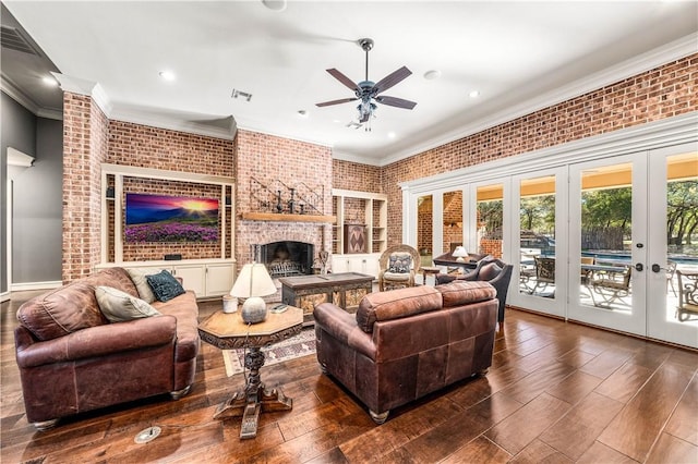 living room featuring french doors, a brick fireplace, brick wall, ceiling fan, and crown molding