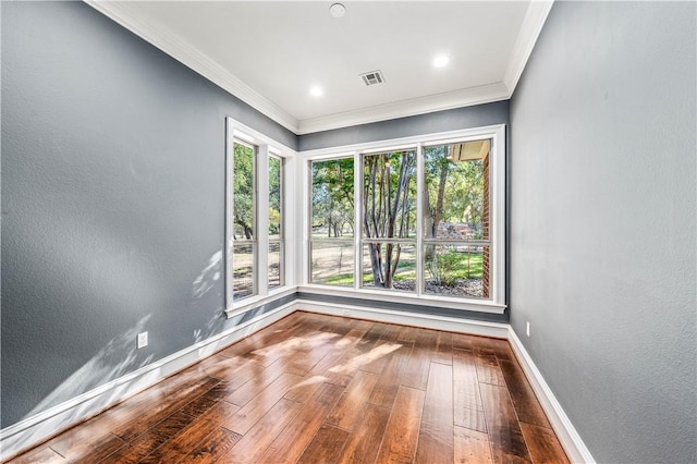 empty room with hardwood / wood-style flooring, a healthy amount of sunlight, and ornamental molding