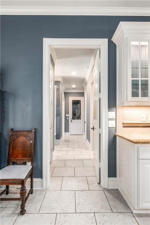 hallway with ornamental molding and light tile patterned flooring