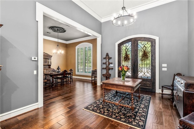 foyer entrance featuring an inviting chandelier, crown molding, dark wood-type flooring, and french doors