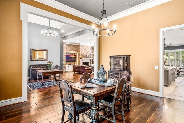 dining room featuring crown molding, a notable chandelier, and a brick fireplace