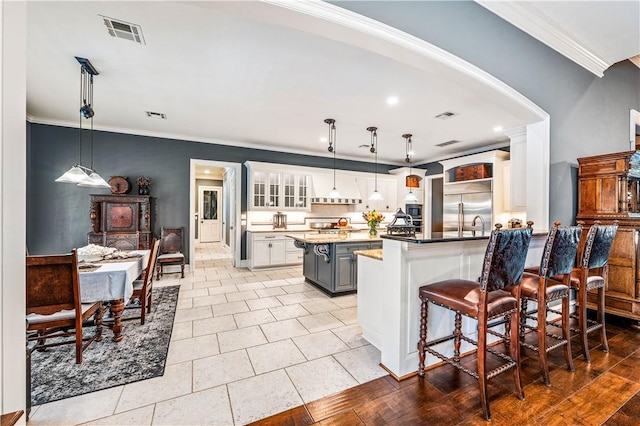 kitchen with stainless steel built in fridge, a center island, gray cabinets, hanging light fixtures, and a breakfast bar area