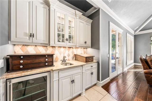 bar featuring white cabinetry, sink, light stone countertops, wine cooler, and crown molding