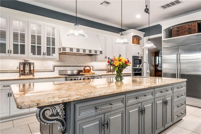 kitchen featuring pendant lighting, custom exhaust hood, a center island, built in appliances, and white cabinetry