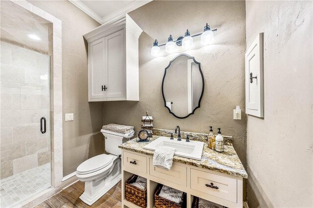 bathroom featuring vanity, toilet, a shower with door, and ornamental molding