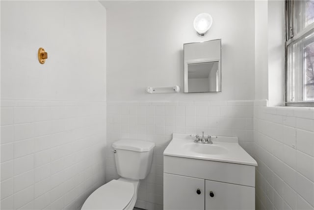 bathroom with toilet, tile walls, and vanity