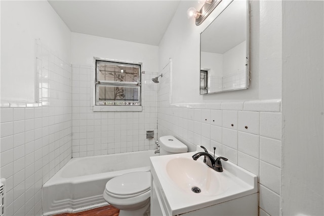 full bathroom with toilet, tiled shower / bath combo, tile walls, and vanity