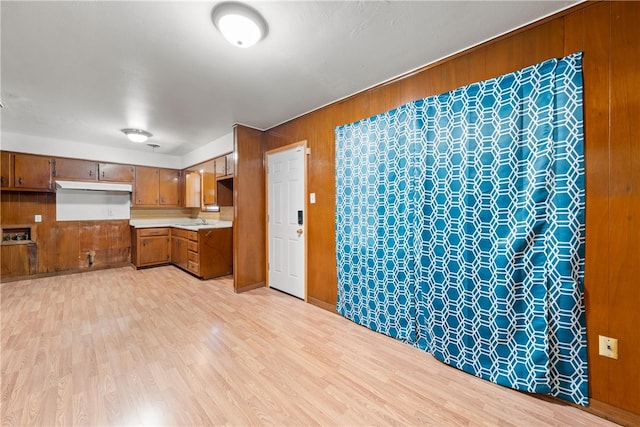 kitchen with light hardwood / wood-style floors, wood walls, and sink