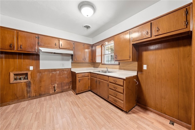 kitchen featuring light hardwood / wood-style flooring, wooden walls, and sink