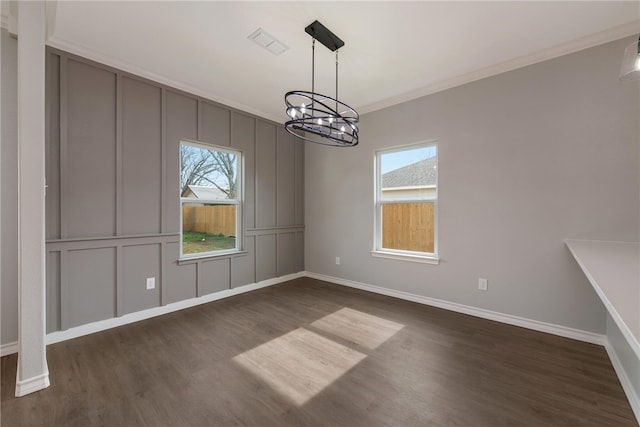 unfurnished dining area with a notable chandelier, dark hardwood / wood-style floors, and crown molding