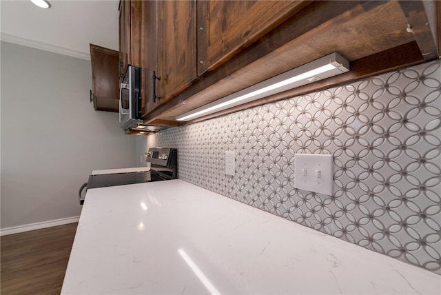 kitchen featuring decorative backsplash, stove, dark hardwood / wood-style flooring, and crown molding