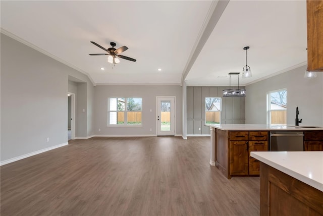 kitchen featuring stainless steel dishwasher, ornamental molding, sink, wood-type flooring, and hanging light fixtures